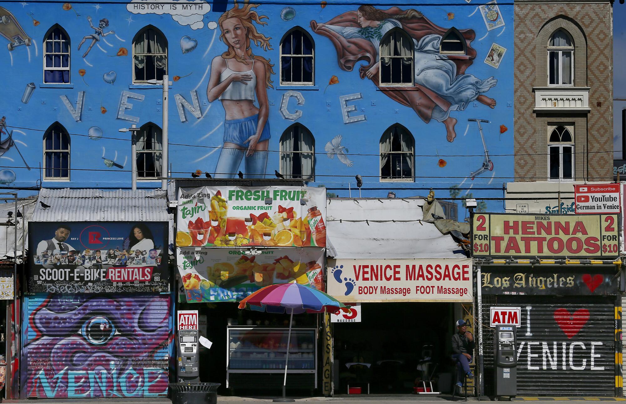 A vendor sits along the empty boardwalk at Venice Beach.