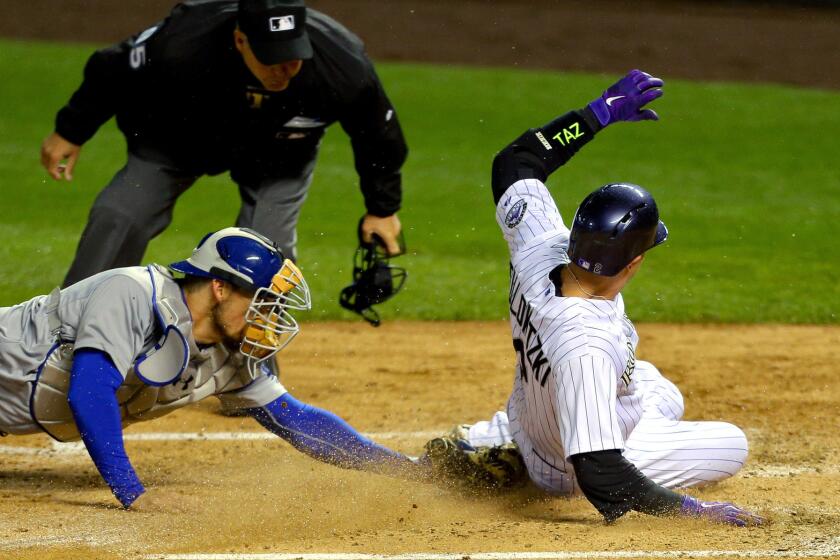 Dodgers catcher Yasmani Grandal tags out Rockies shortstop Troy Tulowitzki as umpire Tim Timmons gets a close look at the play in the fourth inning Friday night in Denver.