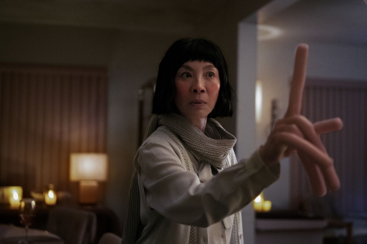 Evelyn (Michelle Yeoh) holds up her hand, consisting of hot-dog fingers, in a scene from "Everything Everywhere All at Once."