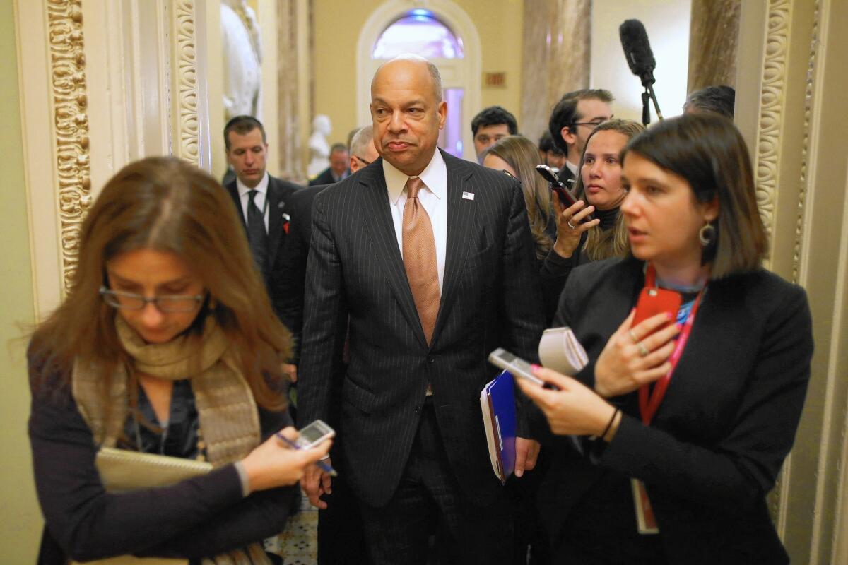 Homeland Security Secretary Jeh Johnson is surrounded by reporters as he moves between meetings with senators to discuss funding his department.