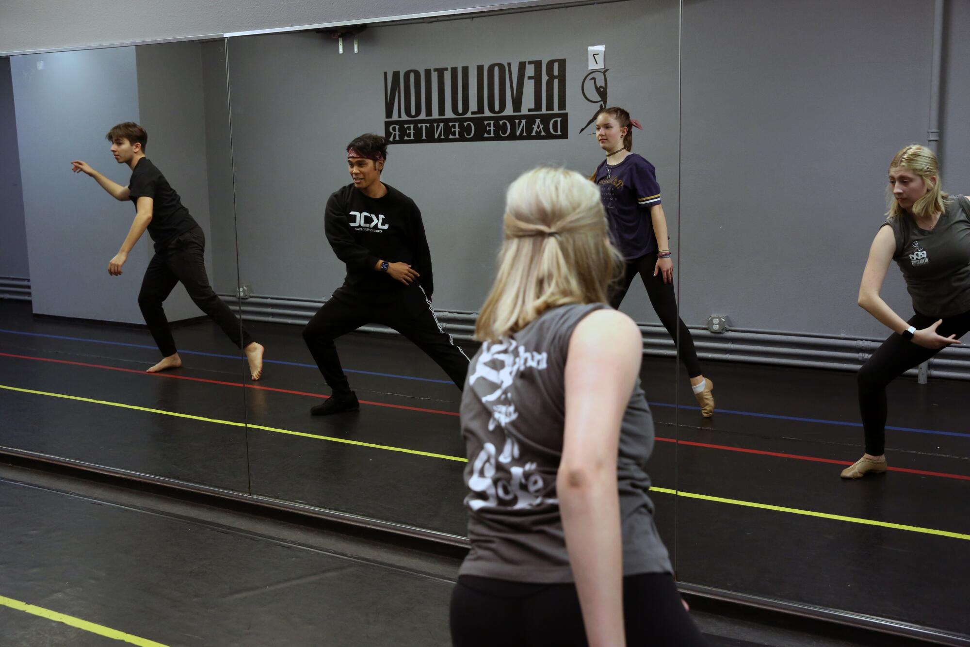 Fred Diaz, second from left, and three dance students reflected in a mirror and a view from behind of one of the students, a blond woman.