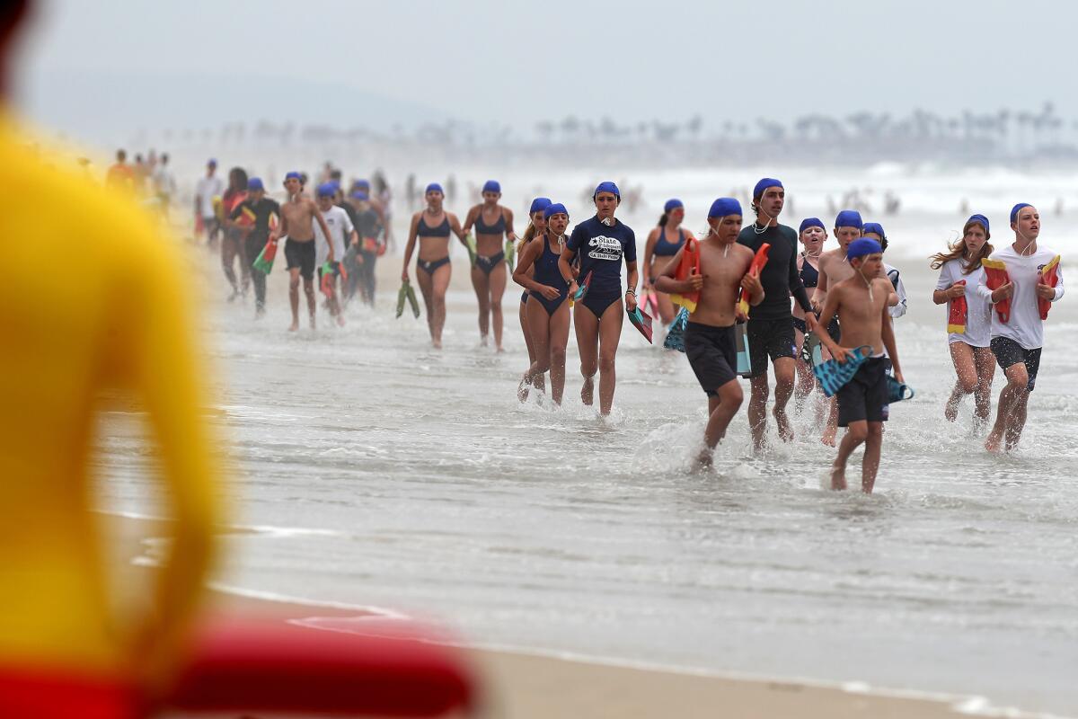Dozens of junior lifeguards participate during a run swim run event at Huntington State Beach on Thursday.