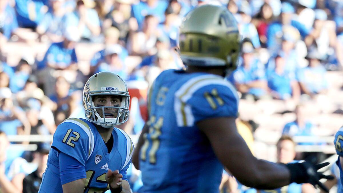While UCLA quarterback Mike Fafaul and tight end Nate Iese are playing in shade at the Rose Bowl, Bruins fans (background) are bathed in sunlight during an afternoon game against Utah in October.