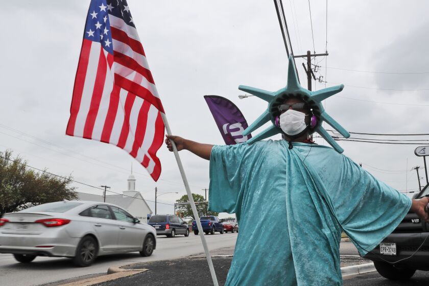 Richard Pruitt waves a flag at passing traffic trying to attract business for Liberty Tax Service located in a strip mall in Dallas, Monday, April 6, 2020. Amid concerns of COVID-19, U.S. tax filing deadline has been pushed to July. (AP Photo/LM Otero)