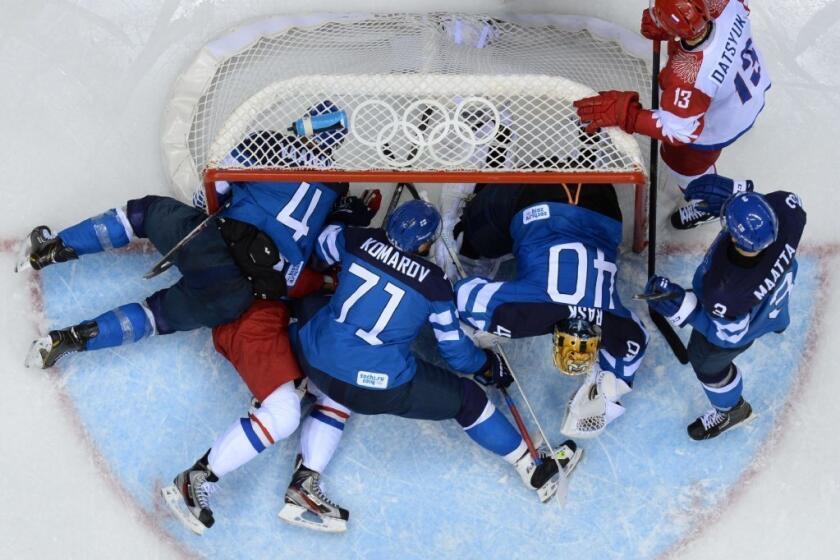Players for Finland and Russia battle in a scrum in front of Finland's net during the Olympic men's hockey tournament in Sochi, Russia.