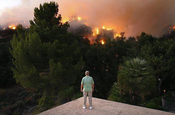 Roger Daniels, a La Crescenta resident since 1964, watches a backfire from the edge of his roof.