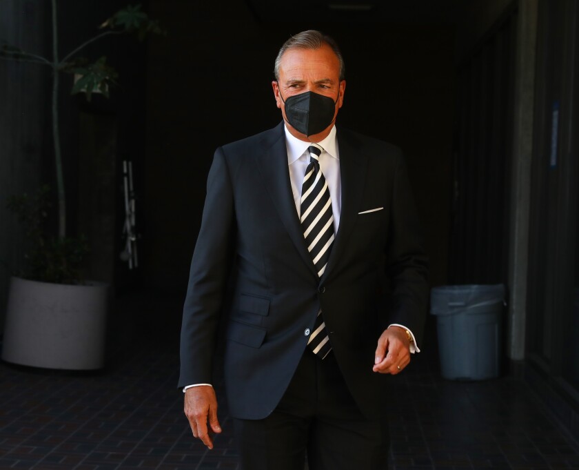 A man in a suit and tie and wearing a face mask seen inside a city building.