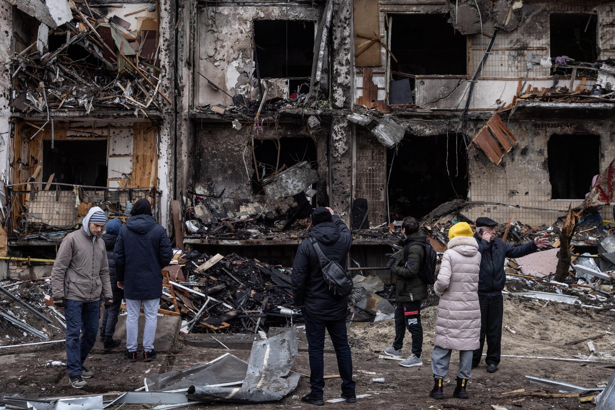People survey an apartment building damaged by a missile strike in Kyiv on Feb. 25.