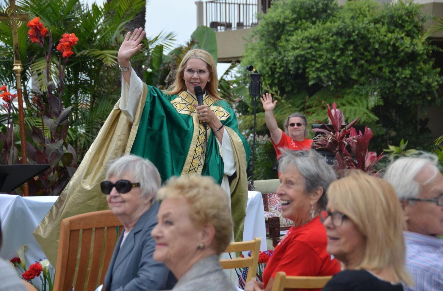 The Rev. Canon Cindy Evans Voorhees waves to a passing firetruck sounding its sirens during the outdoor service held Sunday.