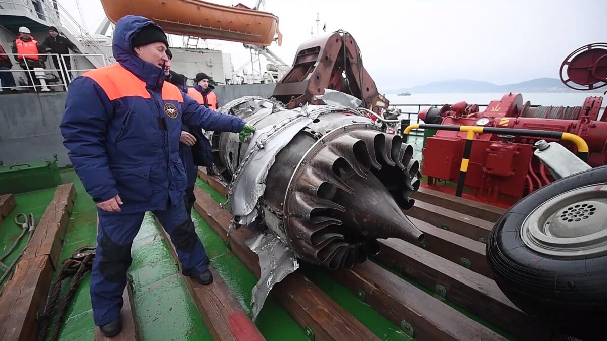 Rescuers examine fragments of the engine and landing gear of the crashed Tu-154 military plane after lifting it from the Black Sea.