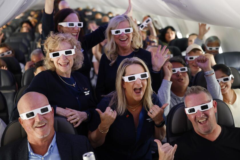 Wearing solar eclipse glasses, the flight crew, takes a photo with passengers.