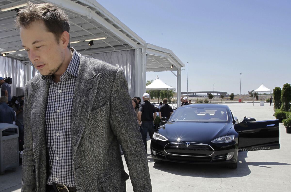 Tesla CEO Elon Musk walks past a Tesla Model S at the automaker's factory in Fremont, Calif.