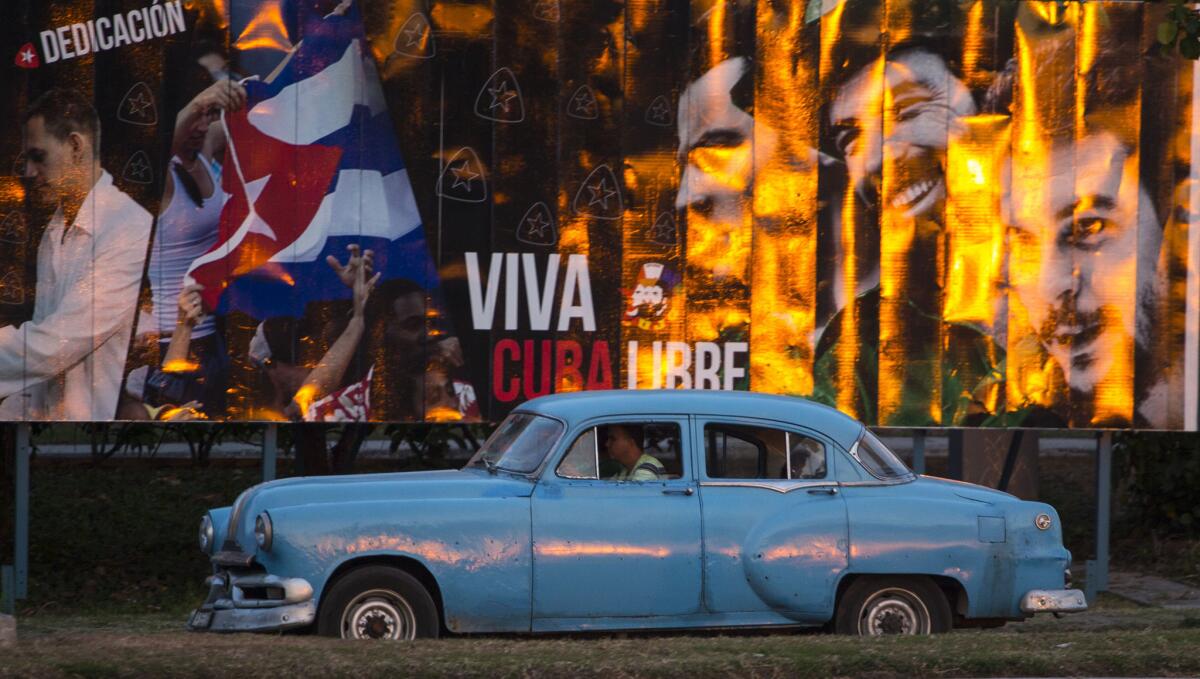 A cabdriver in a classic American car passes a billboard that reads in Spanish, "Long live free Cuba," in Havana on March 14.