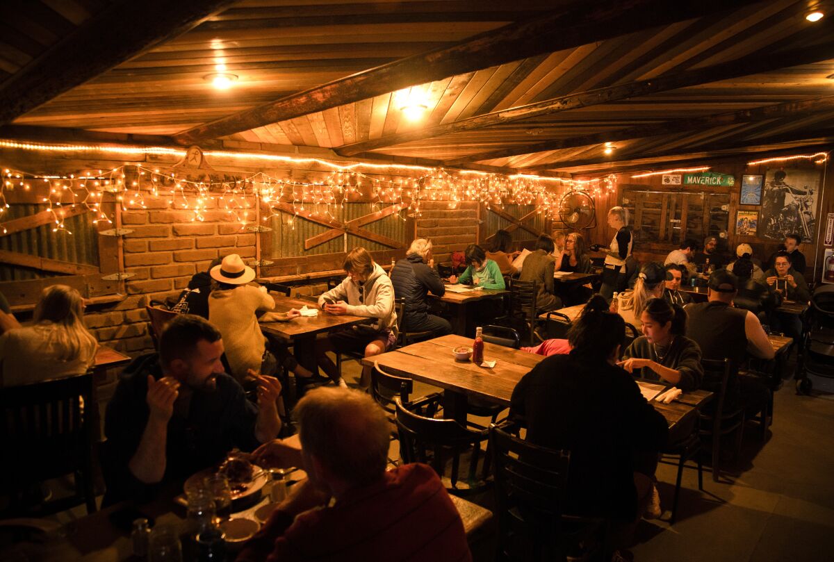 A dining room with a wooden ceiling, lit up by white icicle lights.