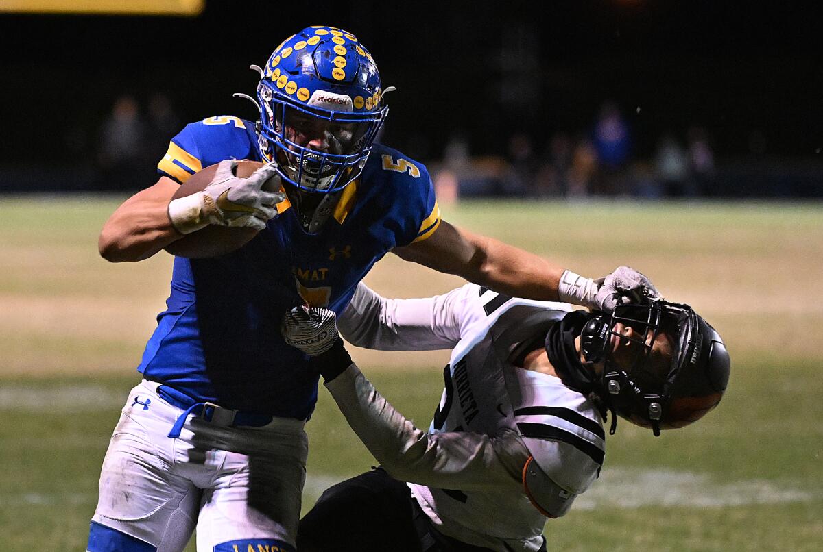 Bishop Amat running back Aiden Ramos fends off a Murrieta Valley defender with a stiff-arm.