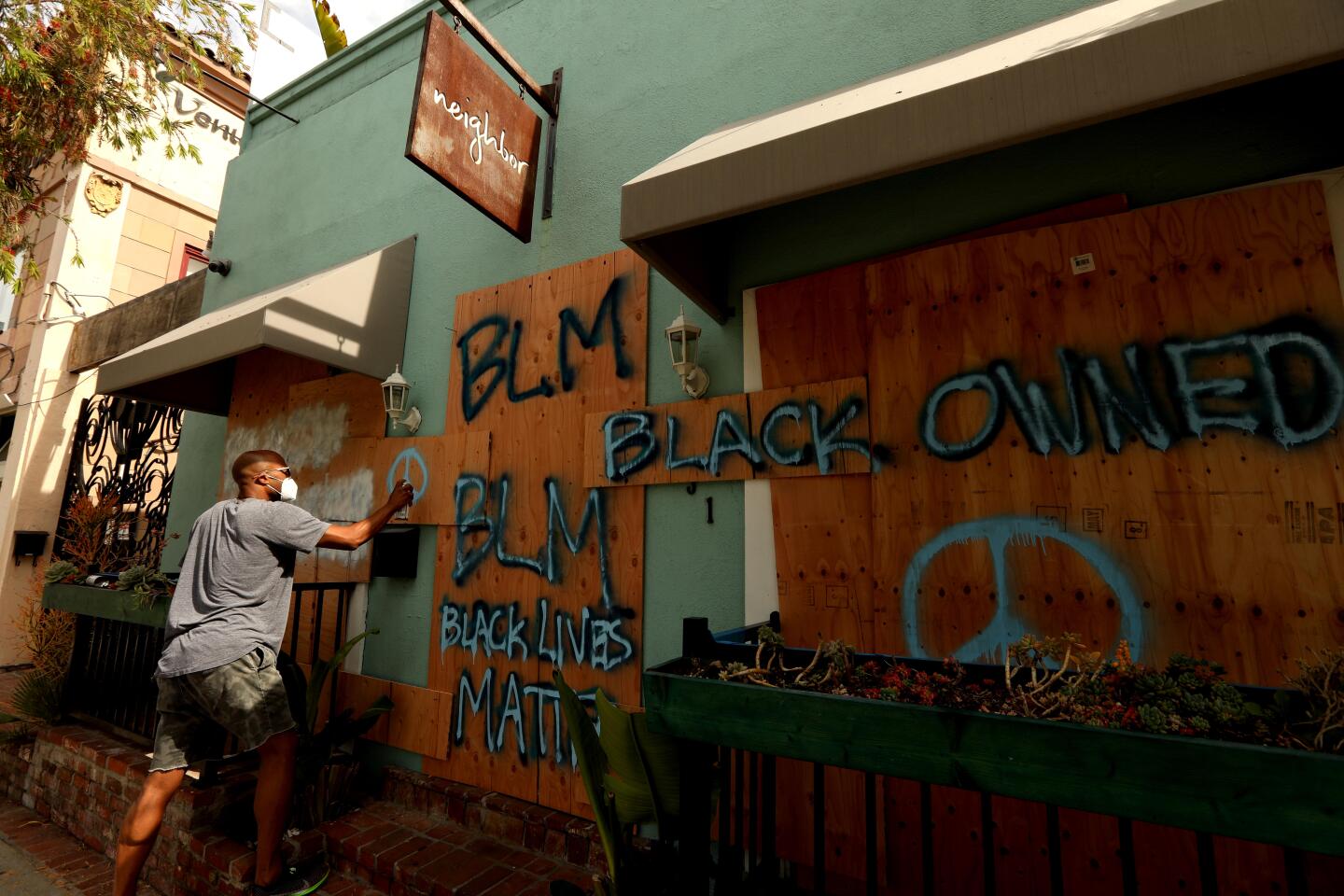 Kristian Vales, owner of a restaurant, spray-paints a message to protesters along Abbot Kinney Boulevard in Venice.