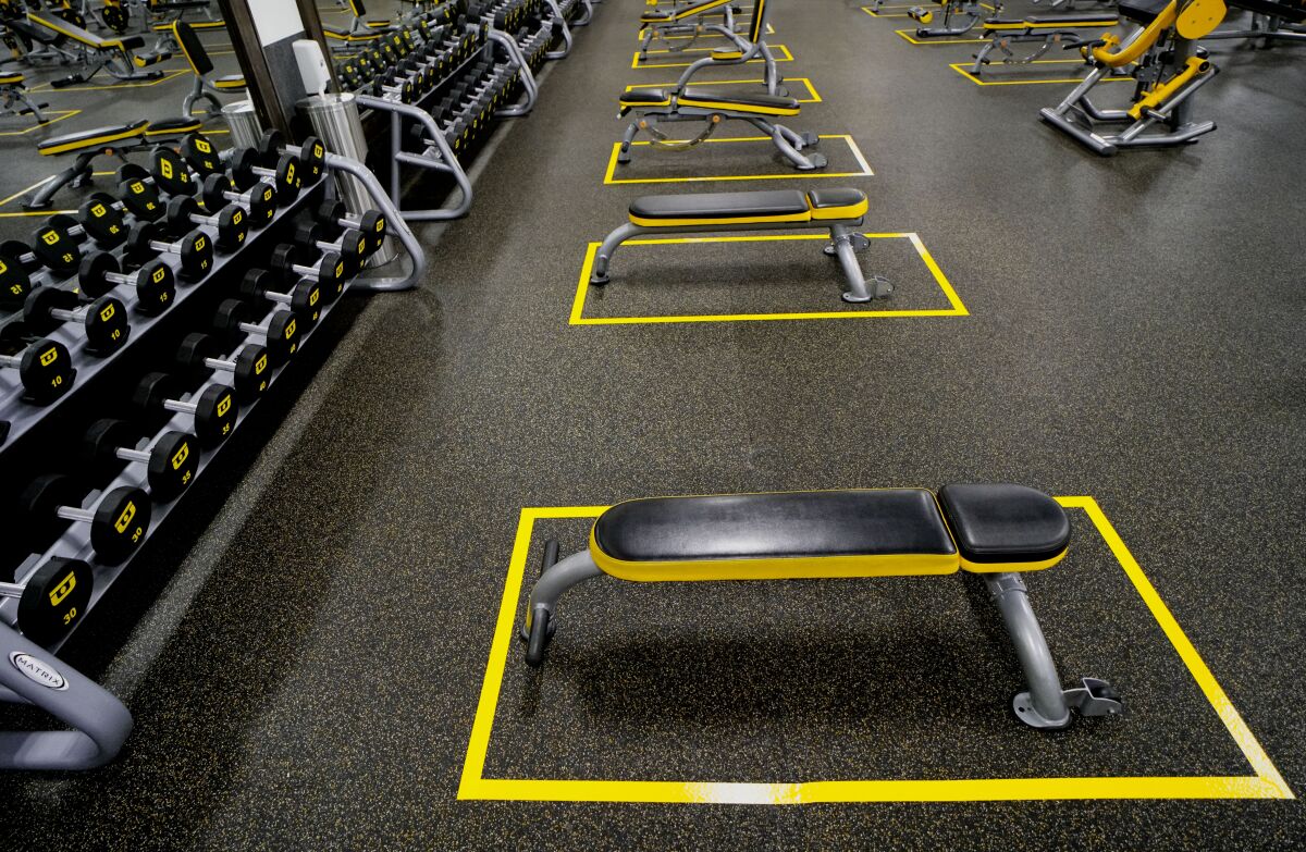 Tape lines around exercise benches mark social distancing guidelines at Chuze Fitness in Chula Vista.