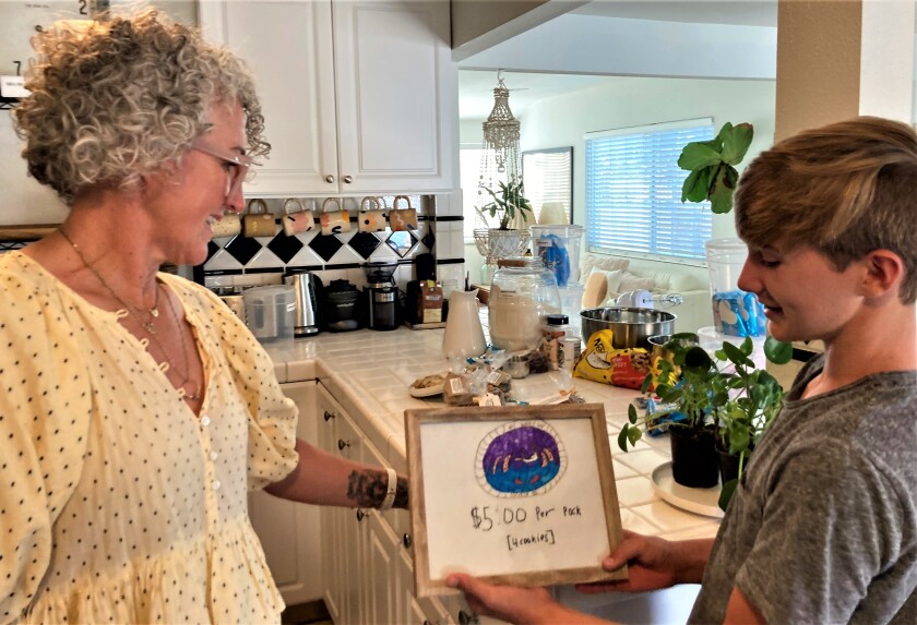 Costa Mesa mom Yvette Rogers, left, with son Jasper display an old handmade logo for his budding cookie business.