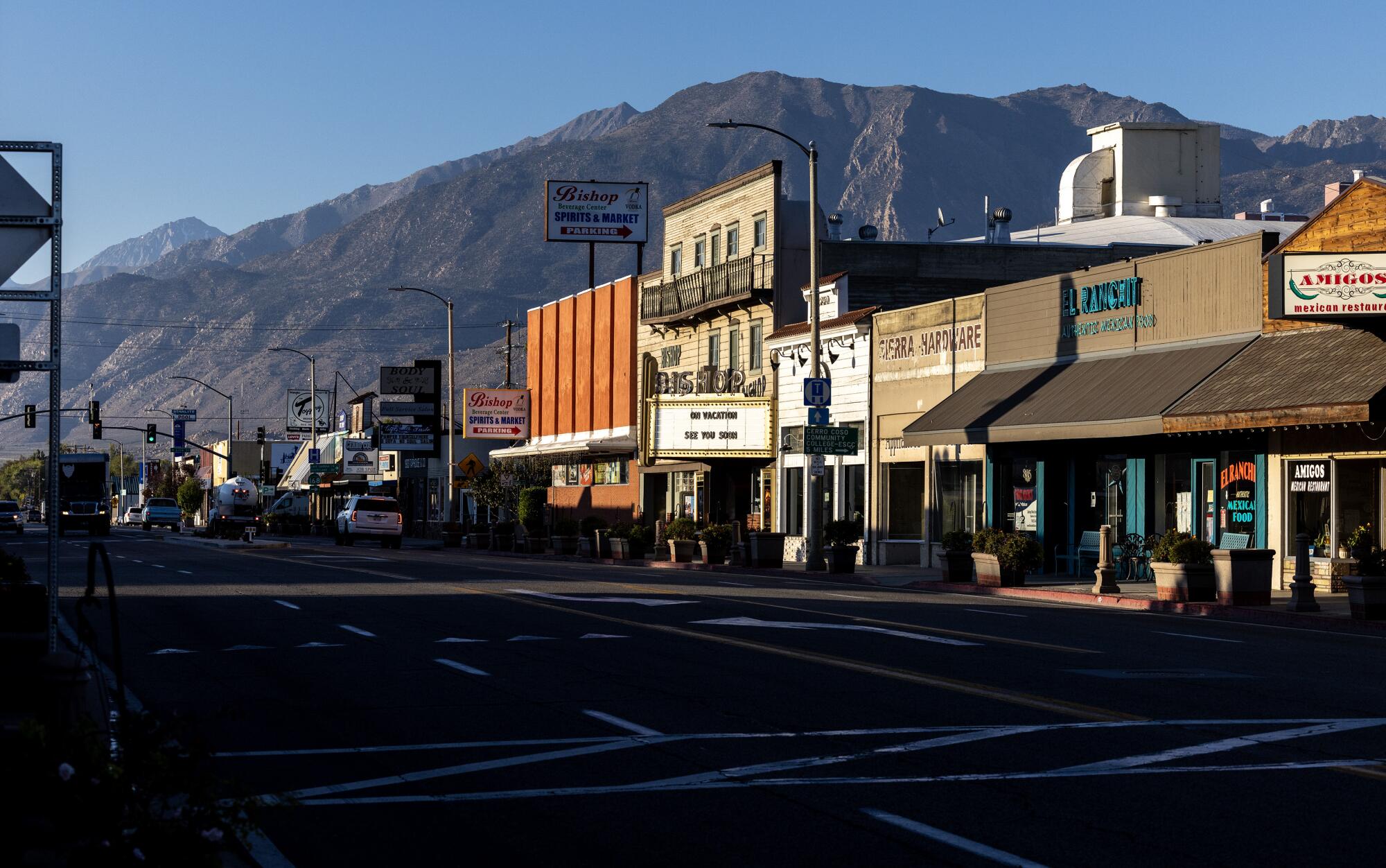 A view down the street of small town toward mountains in the distance.