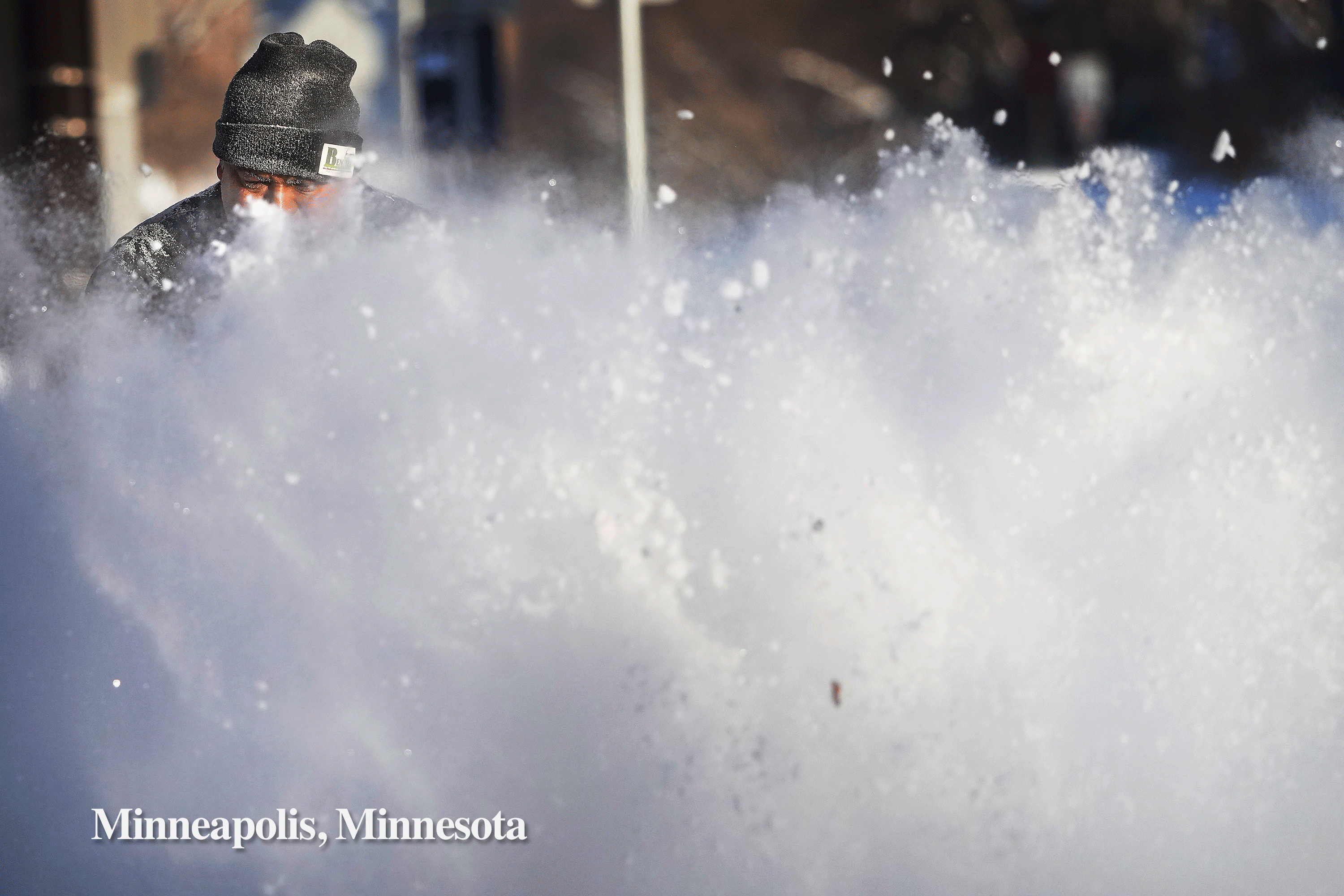 Javier Galicia clears snow from a sidewalk along 4th Ave. in Minneapolis and Angelenos reflected in a glass facade in dtla