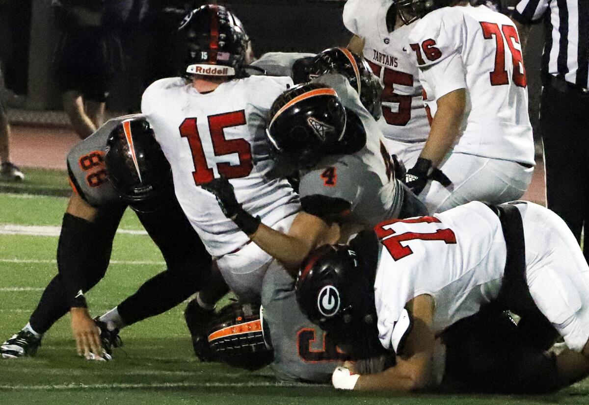 Huntington Beach's Nathan Dumesnil (88), Zack James (4) and Jaxson Brown (6) tackle Glendora's Matthew Jordan (15) on Friday.