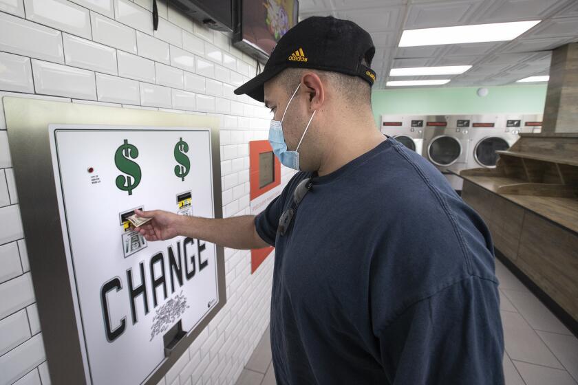 LOS ANGELES, CA -JULY 23, 2020: Adrian Aguilar of Los Angeles gets change in quarters from a $5 bill at SpinCycle Laundry Lounge in Los Angeles, before feeding them into the washing machine and dryer to do his laundry. There is a nationwide coin shortage and laundromats have been particularly affected since customers might not always walk in with enough quarters to do their laundry. (Mel Melcon / Los Angeles Times)