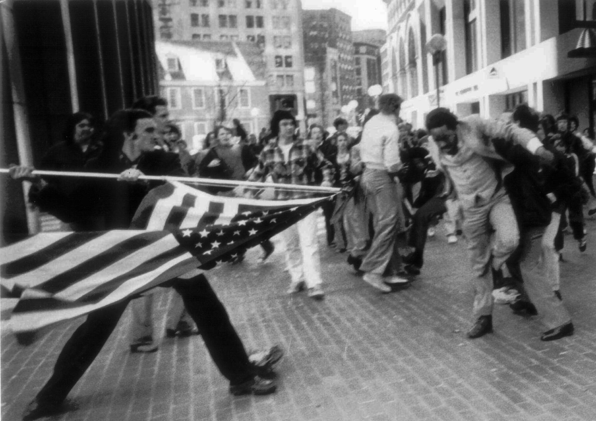A white anti–busing demonstrator uses an American flag to attack a Black man