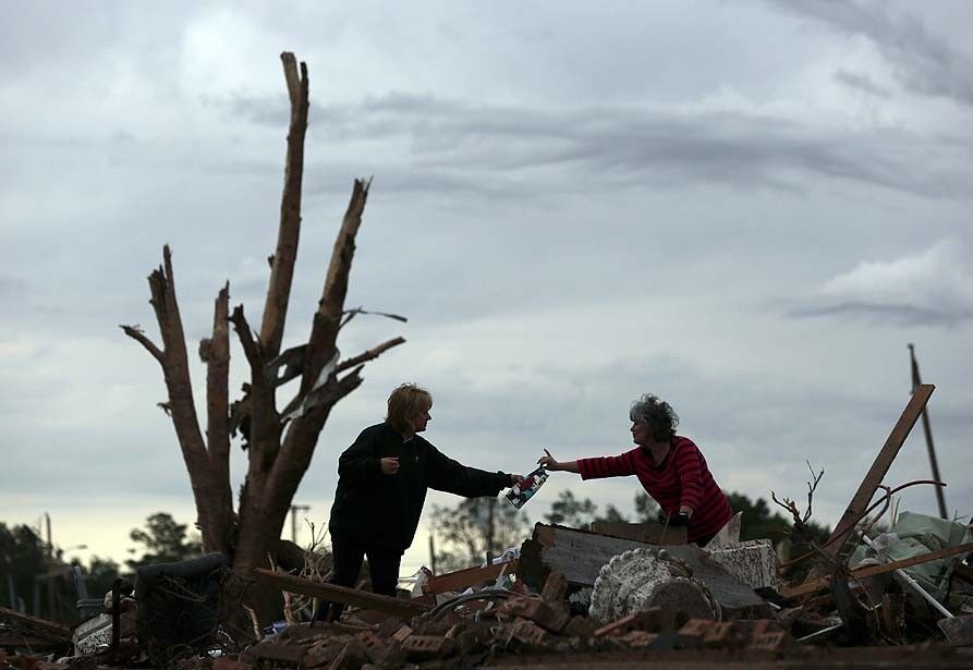 Two women sort through debris as they look for belongings in a leveled home the day after a tornado hit in Moore, Okla.