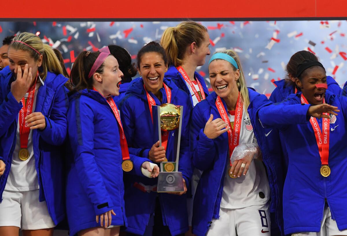 Carli Lloyd (with trophy) and USA teammates celebrate after winning the CONCACAF Women's Olympic Qualifying Final.