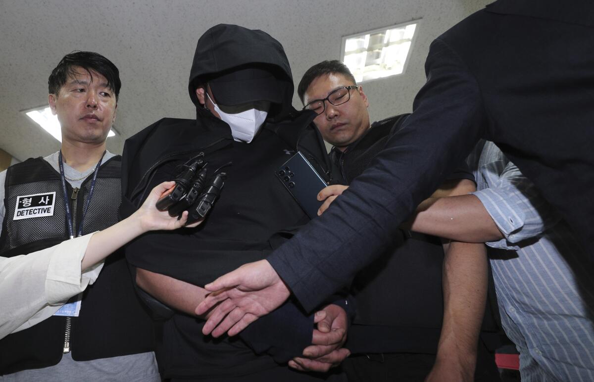 Security personnel surround a defendant in South Korea.