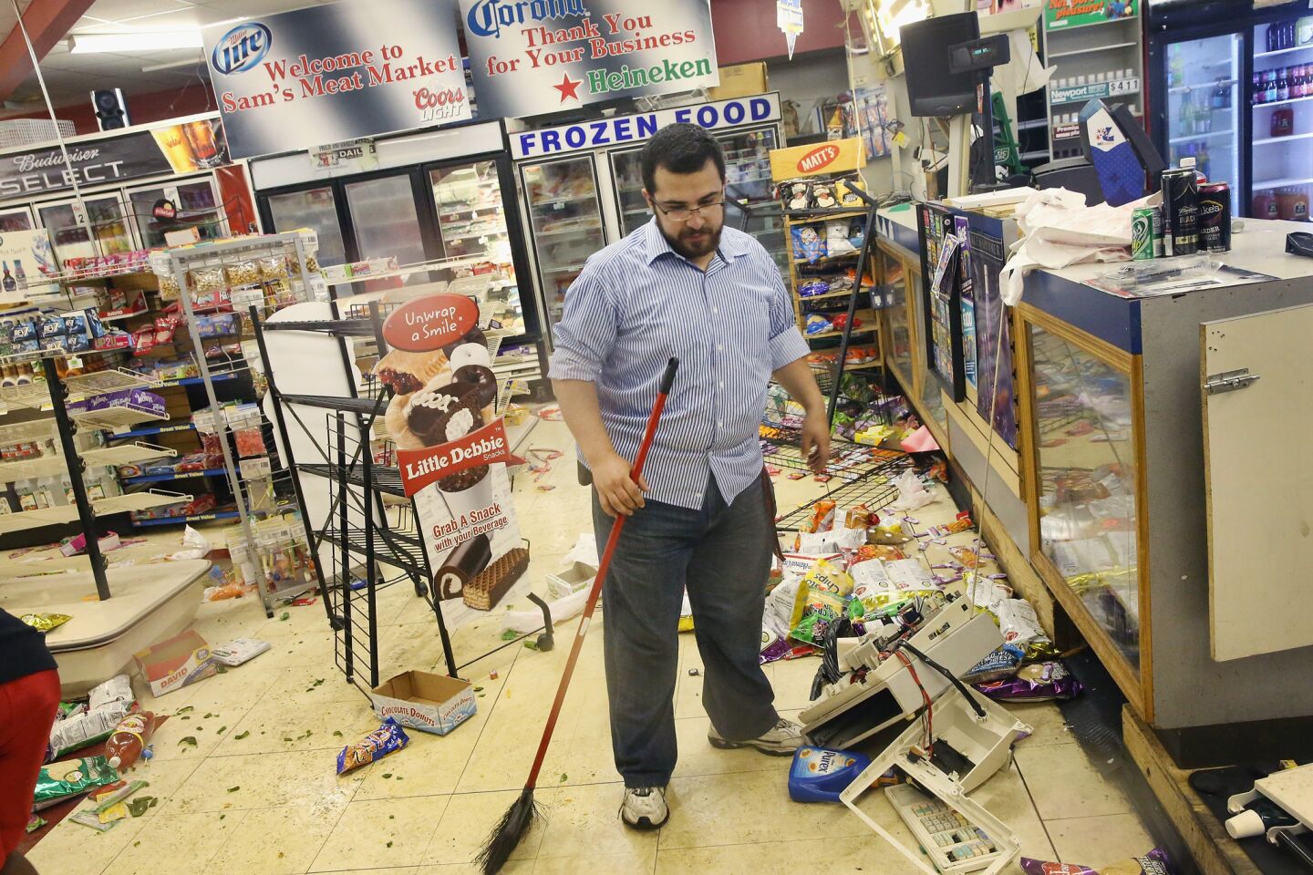 Mustafa Alshalabi cleans up Sam's Meat Market after it was struck by looters overnight.