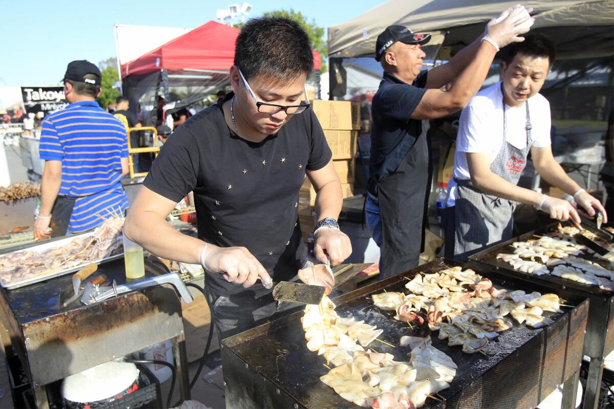 Wenxin Wu, center, with Yiran & Grill in Monterey Park, fries up squid skewers during the OC Night Market. On Friday, the first Monterey Park Night Market event will take place at Barnes Park.
