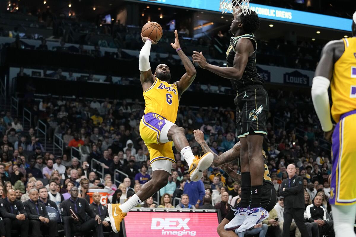 Lakers forward LeBron James hangs in the air as he shoots over Hornets center Mark Williams along the baseline.