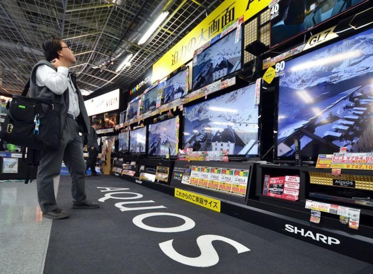 A customer checks LCD television sets by Sharp, which said it will book a record $5.6 billion annual net loss.