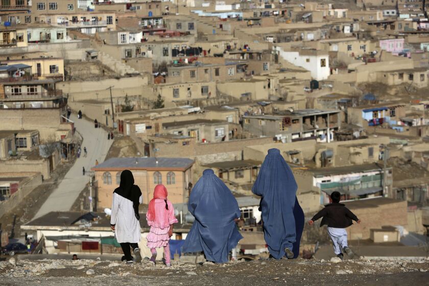 FILE - Burqa-clad women walk on Nadir Khan hilltop overlooking Kabul, Afghanistan on March 16, 2017. Afghanistan’s Taliban rulers on Saturday, May 7, 2022 ordered all Afghan women to wear the all-covering burqa in public, a sharp hard-line pivot that confirmed the worst fears of rights activists and was bound to further complicate Taliban dealings with an already distrustful international community. (AP Photo)