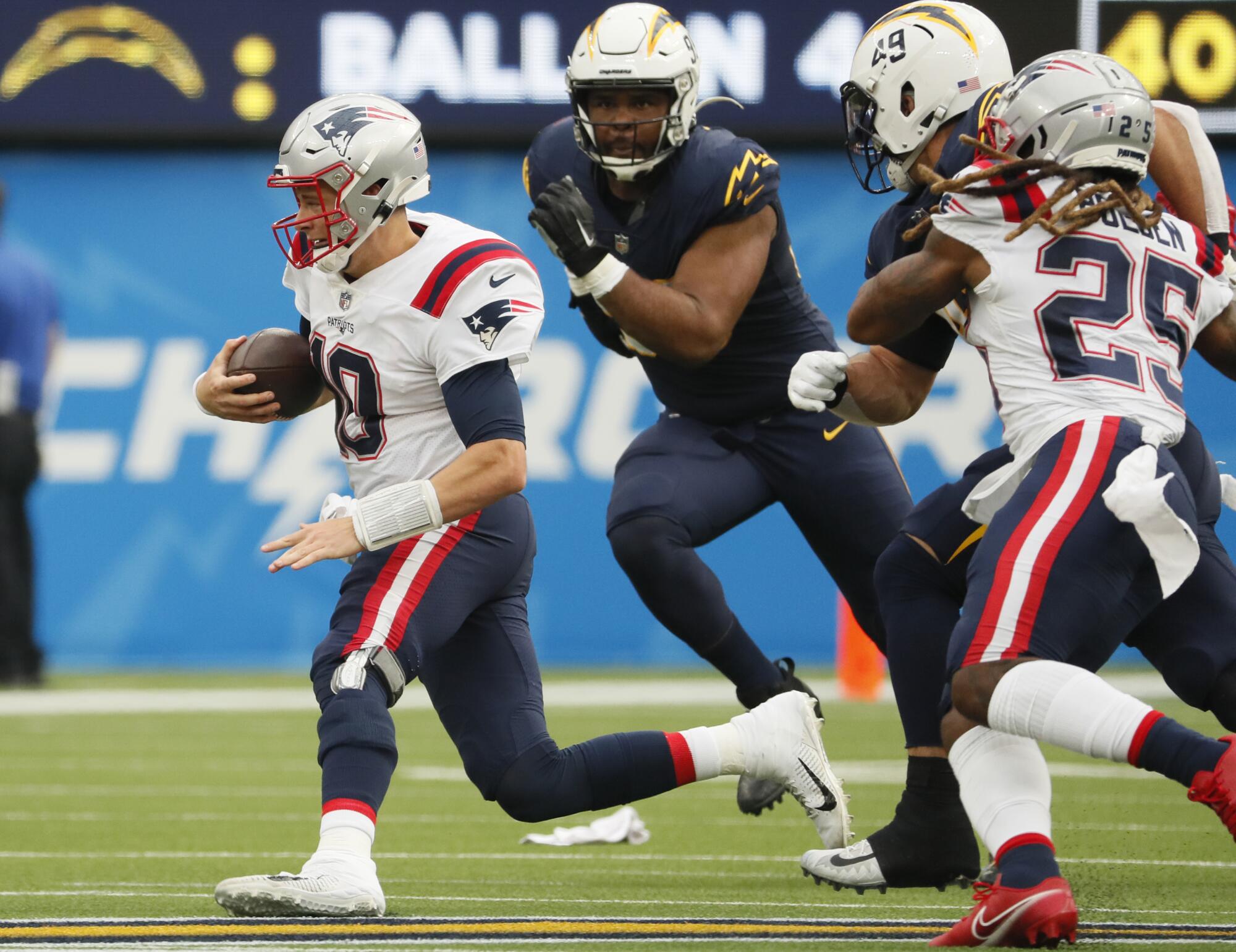 New England Patriots quarterback Mac Jones scrambles as he is chased by the Chargers' defense.