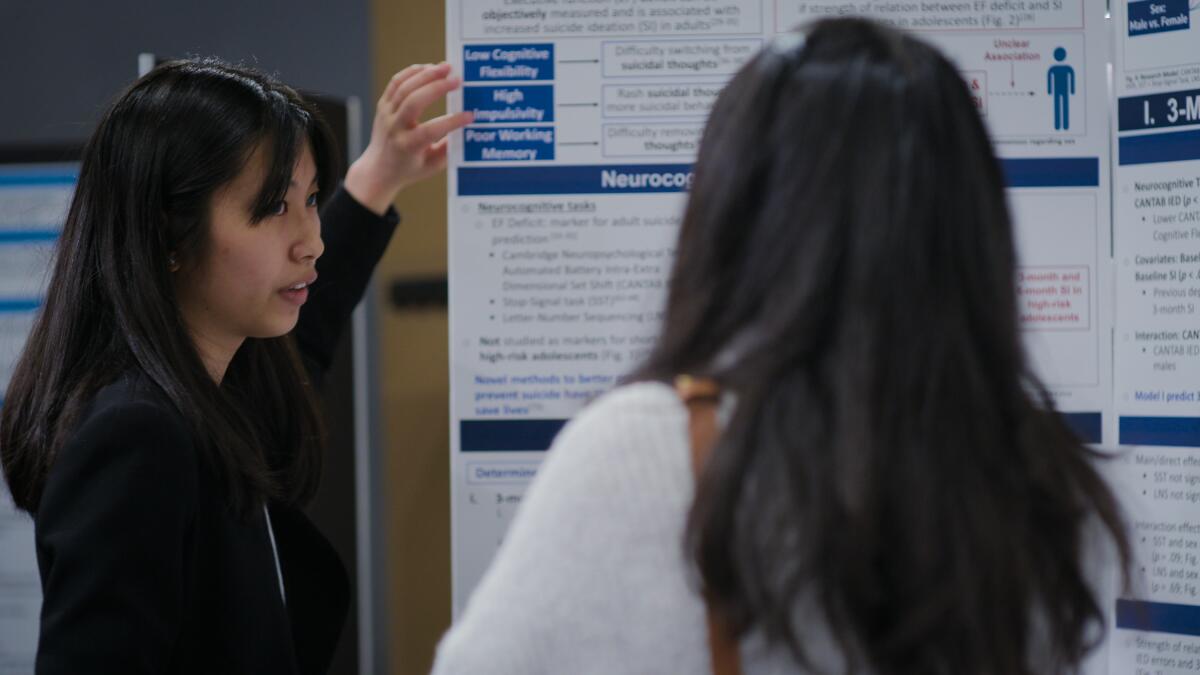 A student at a science fair speaks to a judge