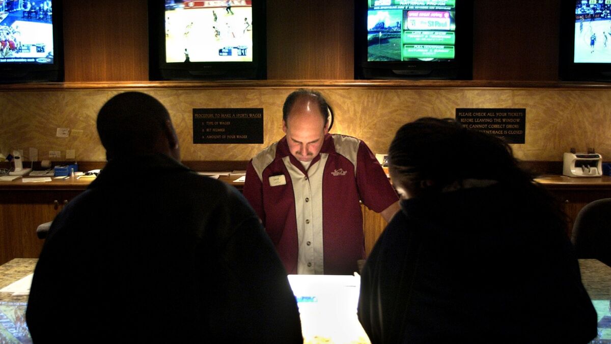 A Mandalay Bay employee takes a bet at the sports book in Las Vegas, where millions of dollars are gambled each week in the fall on college football.
