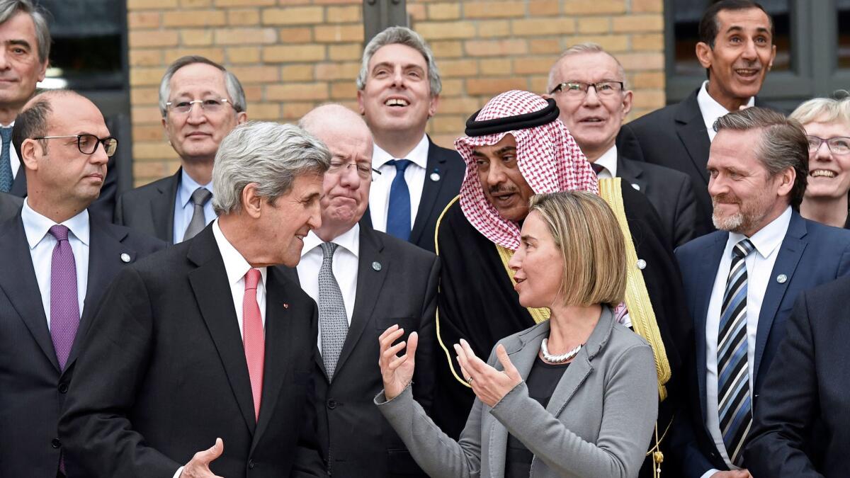 U.S. Secretary of State John F. Kerry speaks with European Union Foreign Policy Chief Federica Mogherini, center right, as they take part with other foreign ministers and representatives in a family picture during a Mideast peace conference in Paris on Jan. 15, 2017.