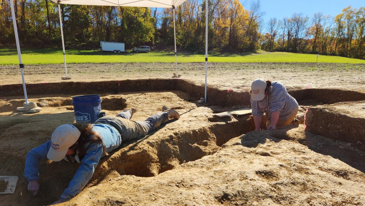 Archaeological workers excavating in a trench