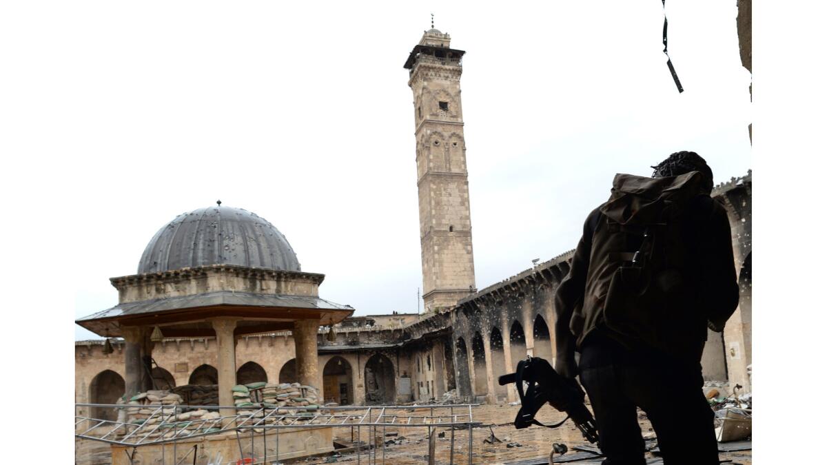 In a 2013 photograph, a rebel fighter faces the mosque's signature minaret, dating to 1090.