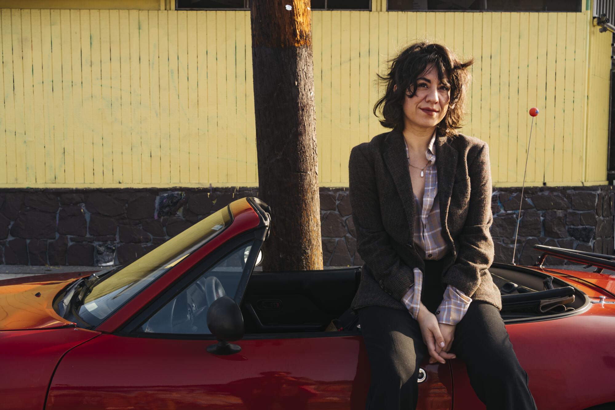 Christina Catherine Martinez, a comedian, writer, and art critic, poses for a portrait with her found Mazda Miata
