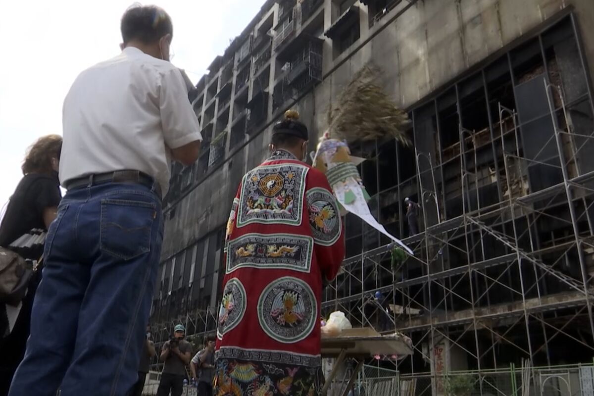 A Taoist priest performs rites outside the burnt building in Kaohsiung in southern Taiwan on Friday, Oct. 15, 2021. Taiwanese officials set up an independent commission Friday to investigate the conditions at a run-down building in the port city of Kaohsiung where a fire killed dozens, while authorities scoured the blackened ruins for the cause of the blaze. (AP Photo/Wu Taijing)