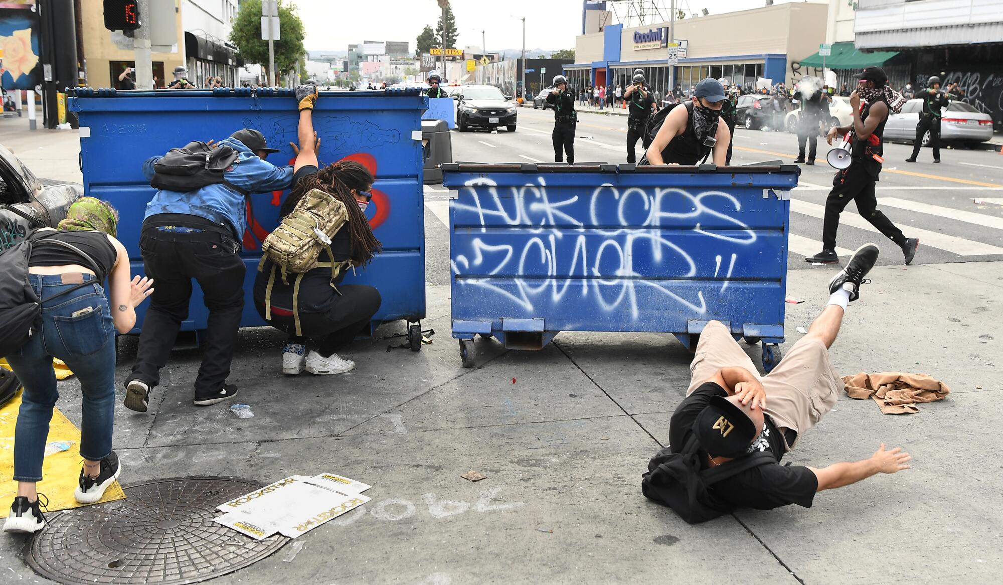 A protester falls to the ground after being shot with a rubber projectile from LAPD officers.