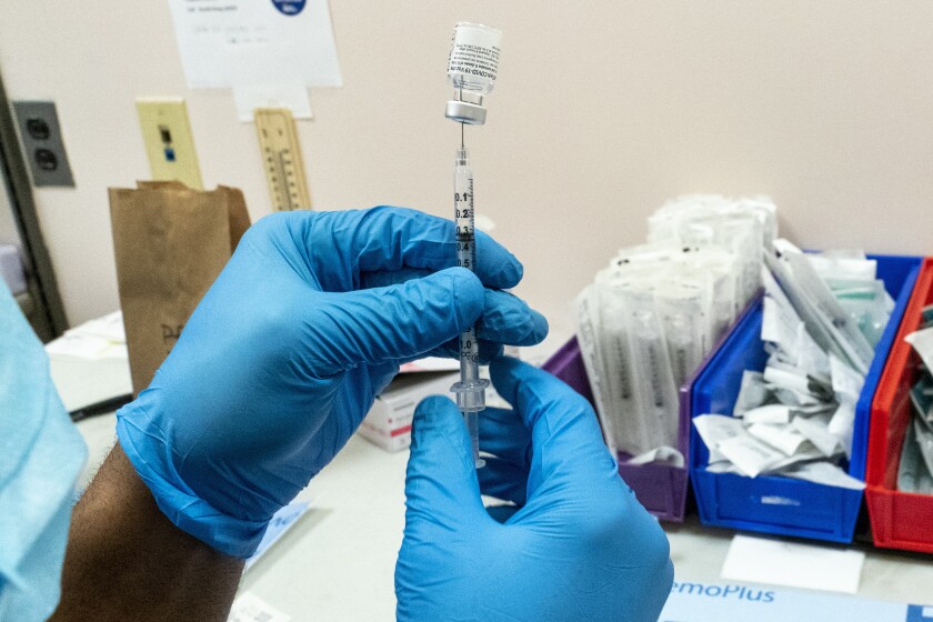 A pharmacist prepares a syringe with Pfizer’s vaccine at a COVID-19 vaccination site in New York.