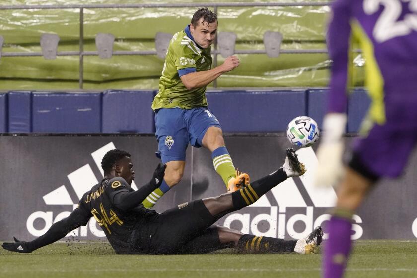 Los Angeles FC defender Jesus David Murillo, left, slides across on a tackle attempt on Seattle Sounders.