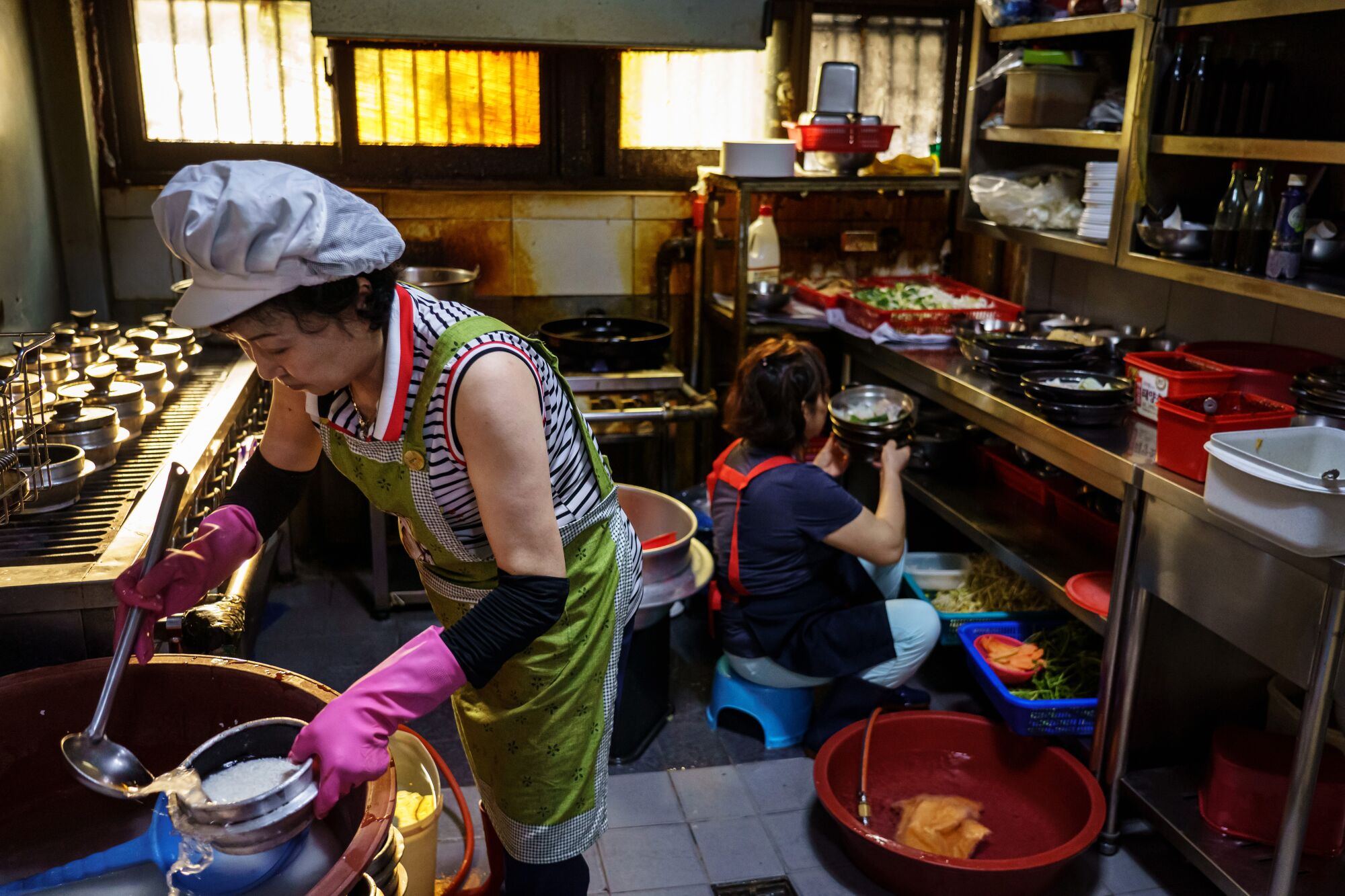 An Ji-shu, left, prepares rice to boil on the stove at Woosung Gisa Sikdang, in Seoul.