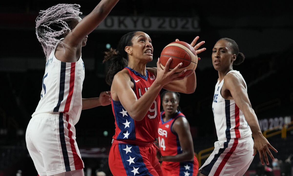 United States' A'Ja Wilson (9), center, drives past France's Endene Miyem (5), left, during women's basketball preliminary round game at the 2020 Summer Olympics, Monday, Aug. 2, 2021, in Saitama, Japan. (AP Photo/Eric Gay)