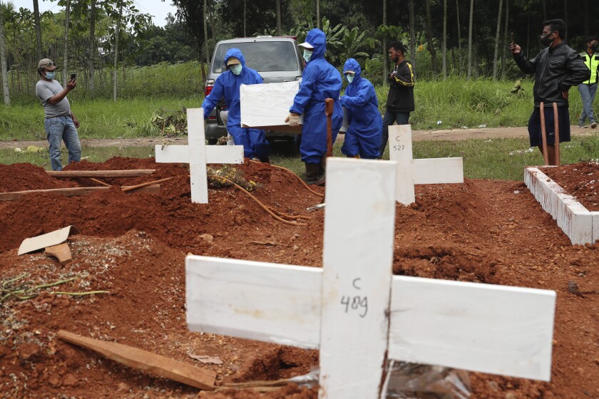 Workers in protective suits carry the coffin of a COVID-19 victim.