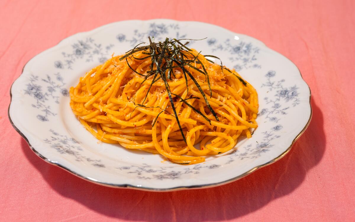 A plate of orange spaghetti topped with strands of nori